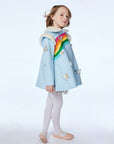A girl poses in the Rainbow Butterfly wool coat, a sky-blue dress coat with a faux fur collar, rainbow detailing, and metallic butterfly appliqués