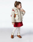 Girl wearing the Little Goodall Lucky Llama Coat, a merino wool jacket with faux fur lining, embroidered llamas, and a hood with a red tassel.