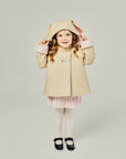 Child in the Luxe Bunny Coat in Sand & Pink, showing off satin cuffs and whimsical bunny ears on the hood.