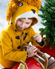 Child in Little Goodall Luxe Lion Coat with hood up, showing lion face design, riding a red sled with a Christmas tree. Warm and playful kids' jacket