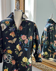Midnight Grand Botanical Shirt on a mannequin, reflected in a mirror. Features a black cotton sateen fabric with a vibrant floral and insect print