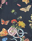 Close-up of the Midnight Grand Botanical Shirt showcasing detailed floral print with butterflies, beetles, and a blue snake on black cotton fabric