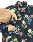 Midnight Grand Botanical Shirt laid flat with a matching straw hat featuring a fabric bow in the same floral and insect print.