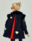 Back view of black girls' winter coat with faux fur collar, gold and silver heart appliqués, and red pleated lining