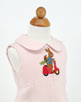 Close-up of Little Goodall Blush Linen Scooter Bunny Dress, showing embroidered bunny on red scooter with basket of vegetables