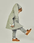 Side view of a child in a grey wool bunny coat with light blue lining, lifting a foot in motion.