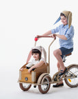 Little boy model wears a tan bunny hat while stirring the bikewagon. The little girl is modeling the oatmeal bunny hat while sitting in the wagon.