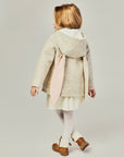Back view of a child wearing a Snowshoe Rabbit Coat, a merino wool hooded jacket with bunny ears, perfect for winter.