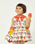 Girl wearing cotton Two Scoops Dress with ice cream pockets and a coral collar, holding an ice cream cone, featuring a fun candy-themed print