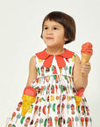 Girl wearing cotton Very Hungry Caterpillar Dress with ice cream pockets and a coral collar, holding an ice cream cone, featuring Very Hungry Caterpillar print fabric.