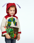 Smiling child wearing a Hungry Caterpillar wool coat with a red hood and antennae, holding the matching book, perfect for toddlers and kids.