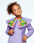 Close-up of a young girl in a purple wool coat with a bold butterfly collar, double-breasted buttons, and colorful embroidery