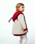 Young girl wearing a Hungry Caterpillar wool coat with red accents and an antennae hood, shown from the back with playful purple antennae detail