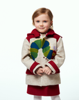 A young girl wearing a Hungry Caterpillar wool coat featuring a whimsical caterpillar applique, red collar, and cuffs, paired with a red dress