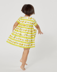 Young girl twirls in a lemon-print dress, showing off its flowy design and playful back view