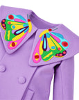 Close-up of a purple wool coat with a large butterfly-shaped collar featuring colorful embroidered details