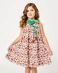 Girl wearing a sleeveless strawberry print dress with a green leaf collar and stuffed strawberry ties, designed for twirling and summer wear