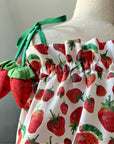 Close-up of strawberry bubble romper with tie-shoulder straps and plush strawberry accents