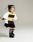 Girl wearing a bumblebee cape with hood and antennae, featuring black and yellow stripes. Playful animal-inspired children's outfi