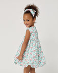 Back view of a girl twirling in a mint carrot-print dress with a gathered waist