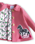 Yolanda and Tatty pink wool coat with zebra appliqué, gold buttons, and printed satin lining featuring zebras and greenery