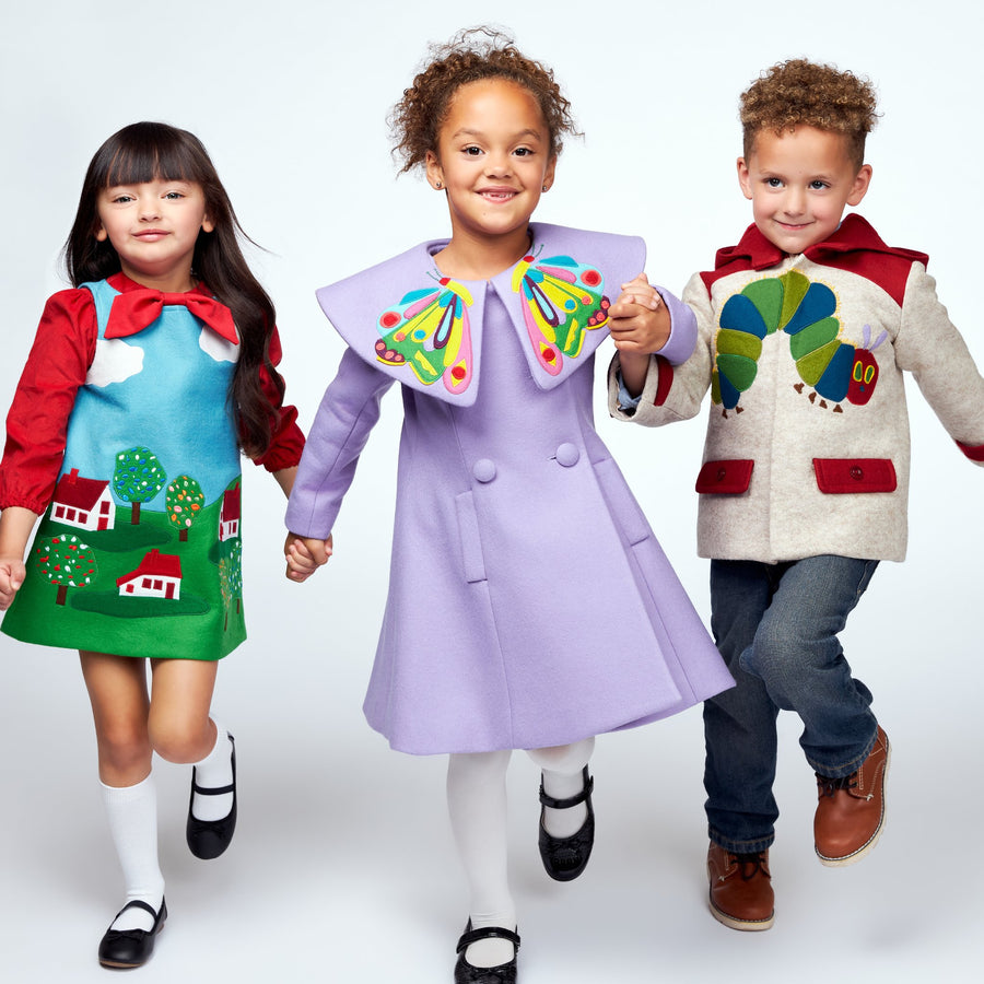 Three children dressed in coats with Eric Carle themes