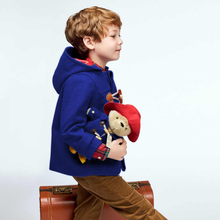 Boy walking in Blue Wool coat with Paddington Bear plush toy under his arm