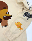 Beige sweater with bear on front and embroidered fish and sheep designs on the sleeve