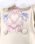 Cream-colored girls coat with decorative pink embroidery and blue birds on a white background