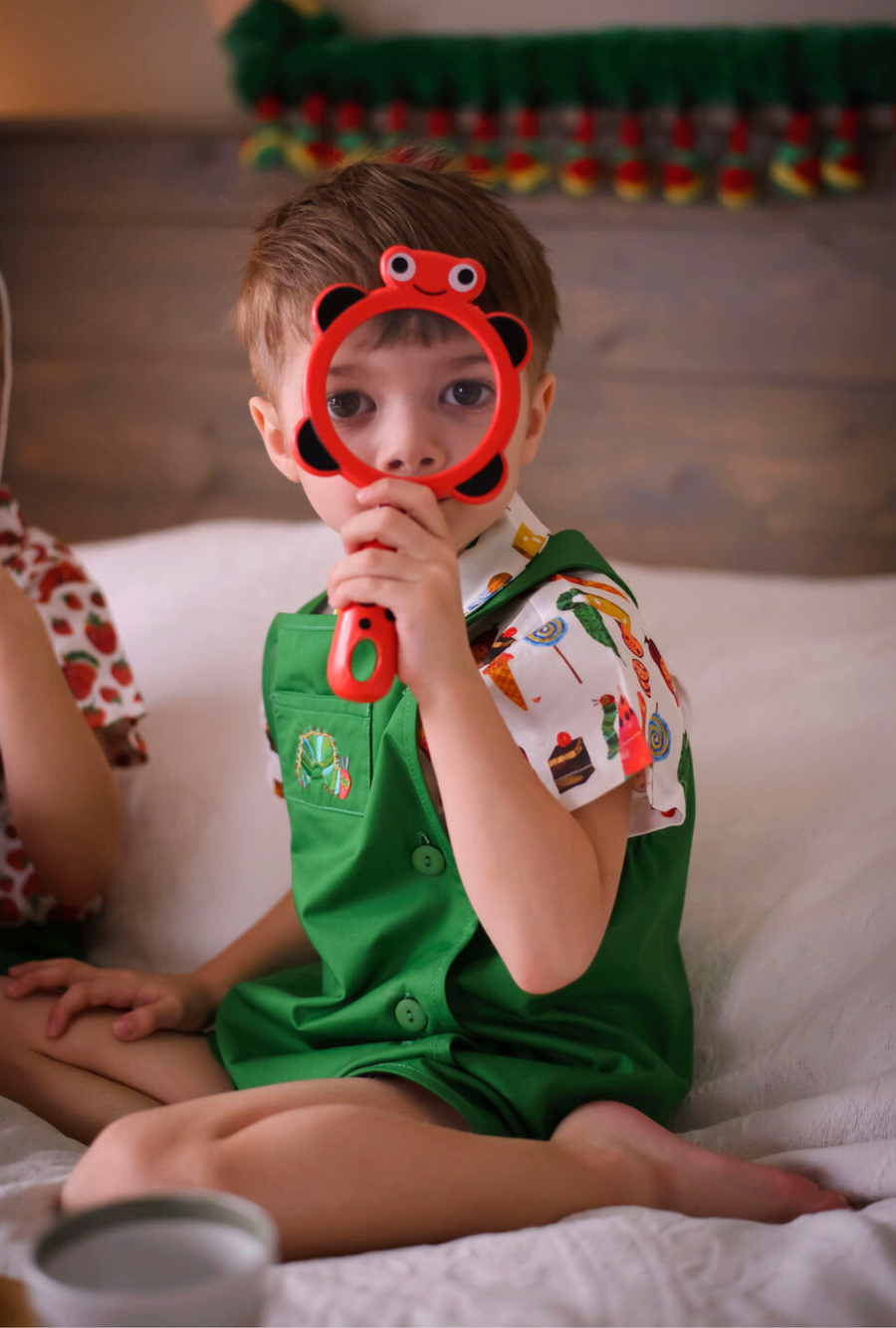 Toddler in a green Hungry Caterpillar romper and food-print shirt 