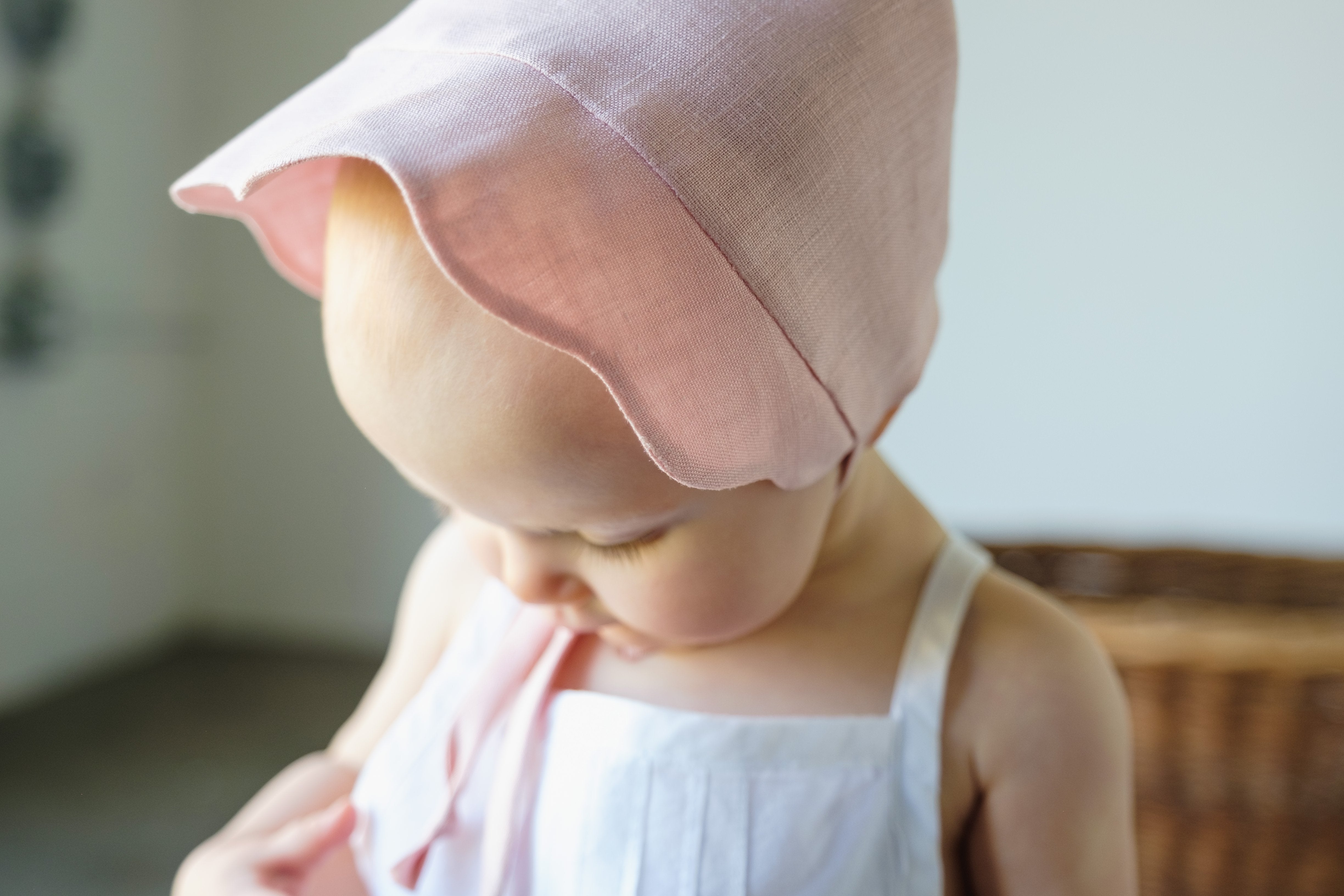 Close-up of baby wearing a shell pink linen scallop bonnet with a soft sun brim.