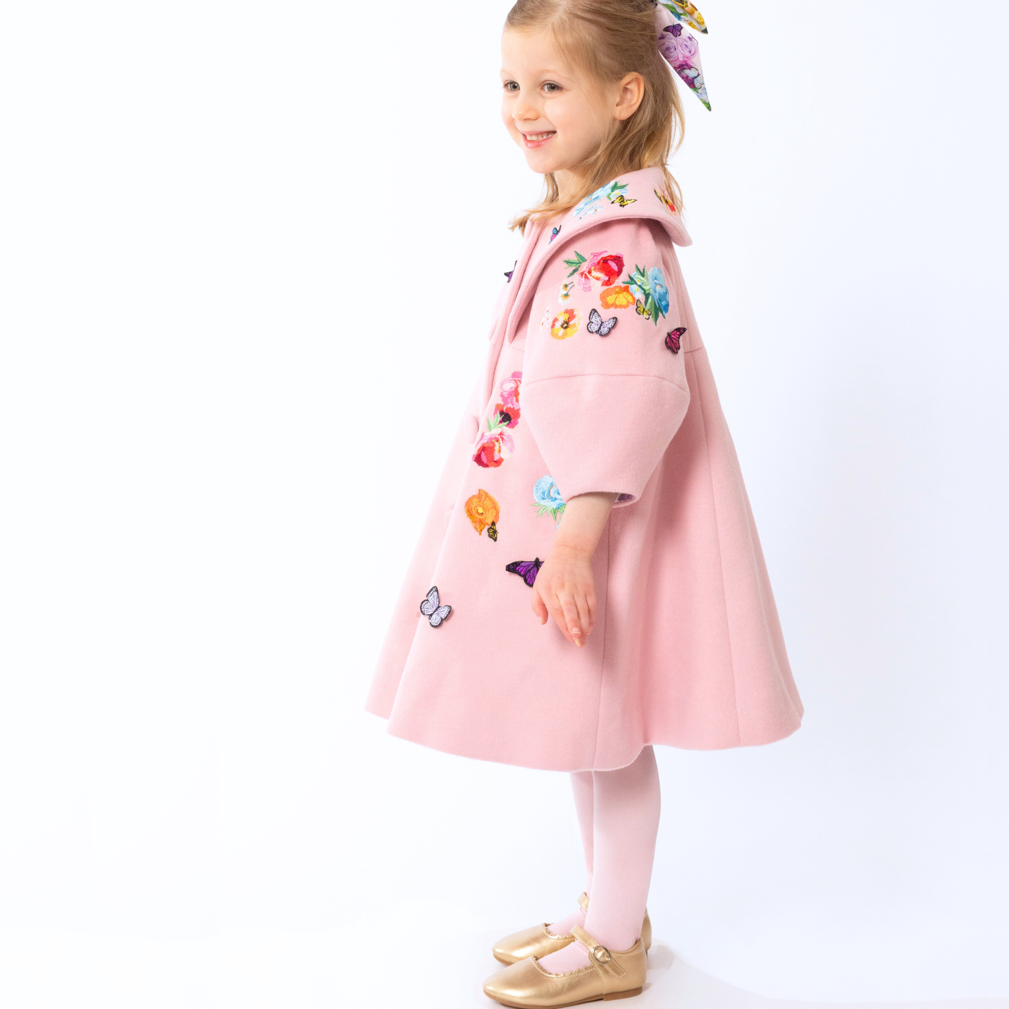 girl wearing a pink wool coat with floral and butterfly embroidery from the Rainbow Bloom , featuring a wide collar and elegant A-line silhouette