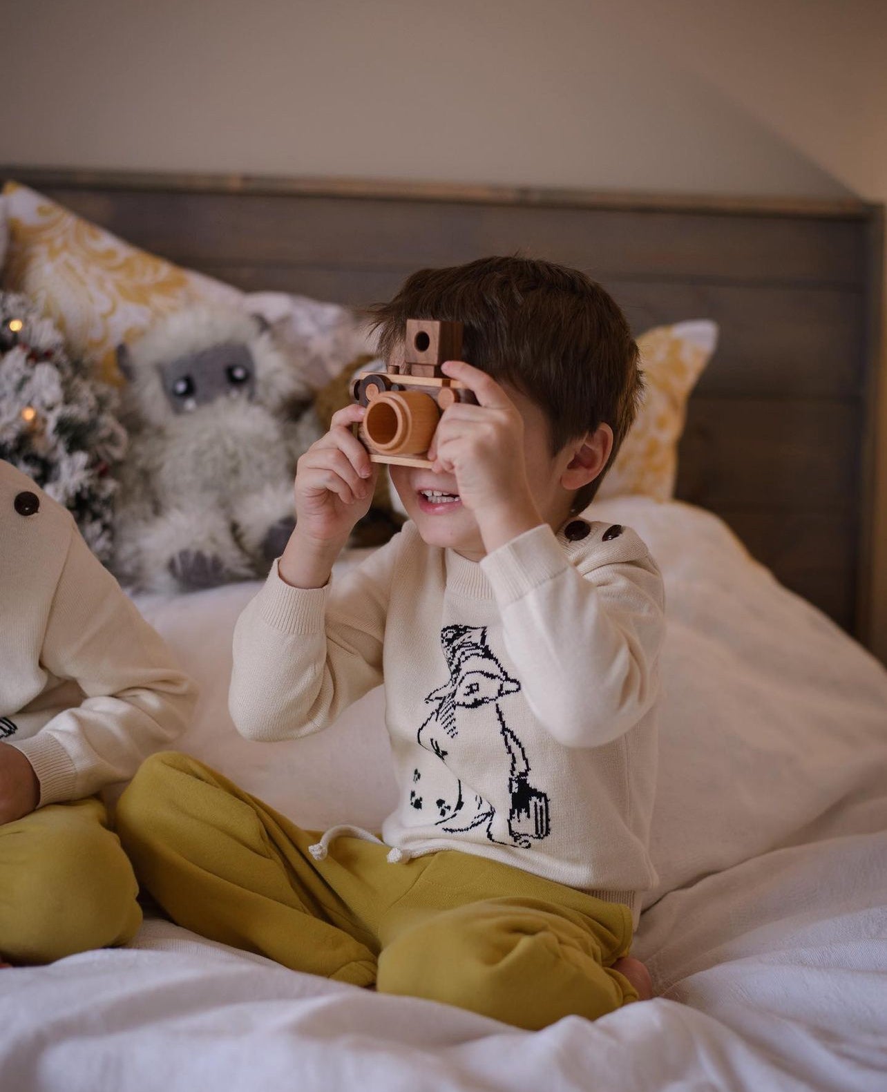 Child wearing the Kids Sweater in ivory, featuring a black knit illustration of Paddington Bear by Peggy Fortnum. Soft 100% cotton, gender-neutral