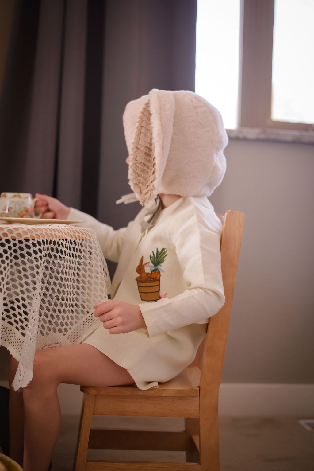 toddler wearing Little Goodall embroidered linen bunny jacket, side view showing bunny and carrot basket design