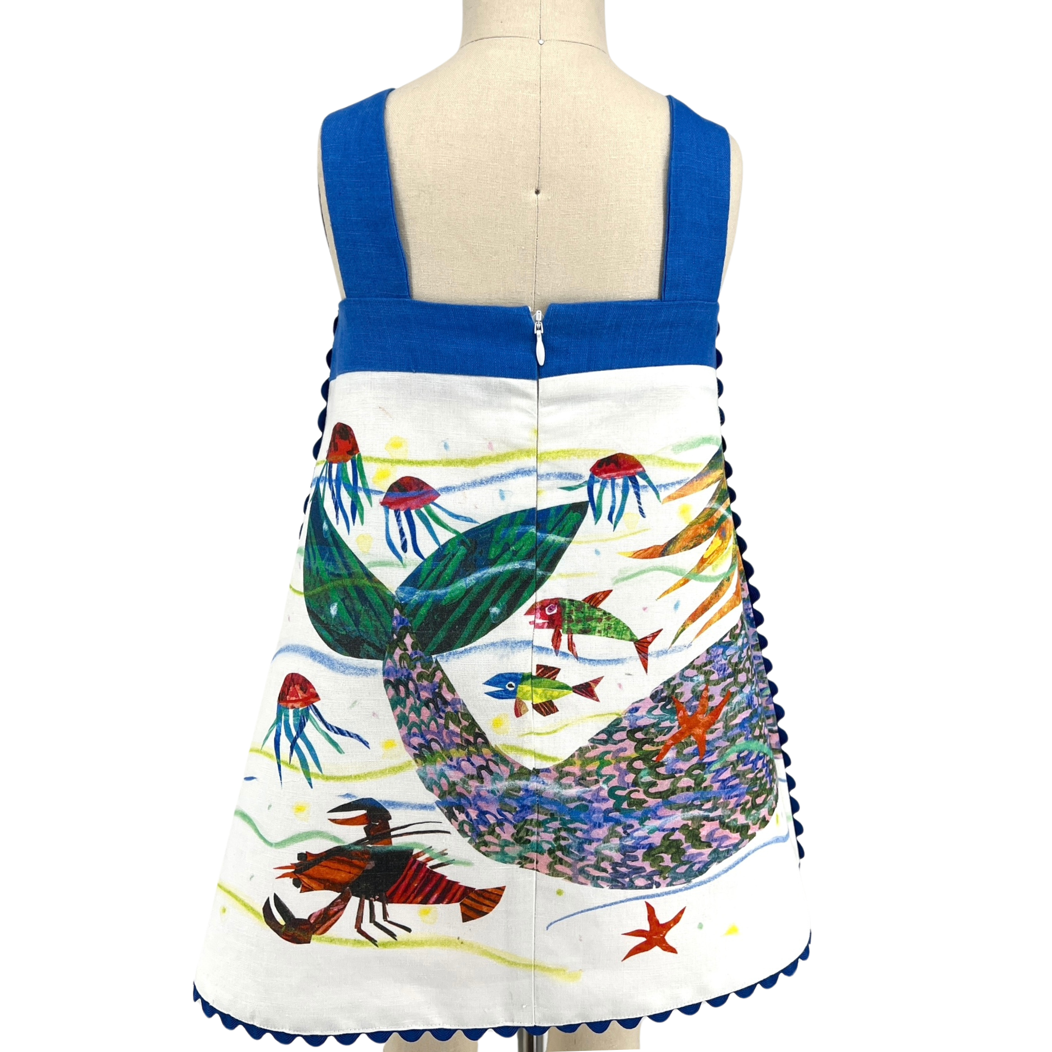 Back view of a sleeveless mermaid dress with blue straps, a central zipper, and an underwater scene featuring jellyfish, fish, and a vibrant mermaid tail