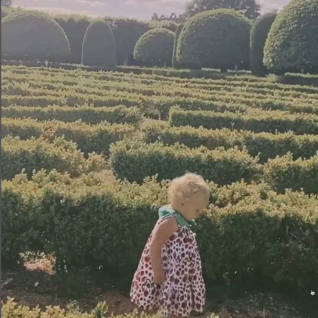 video showcasing A young girl walking gracefully in a strawberry-print dress with a green leaf colla