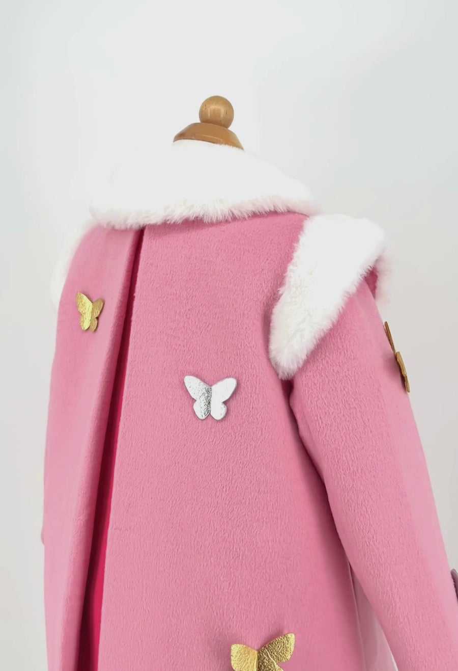 Close-up of pink wool girls' coat with a rainbow, gold and silver butterflies, and a soft faux fur collar