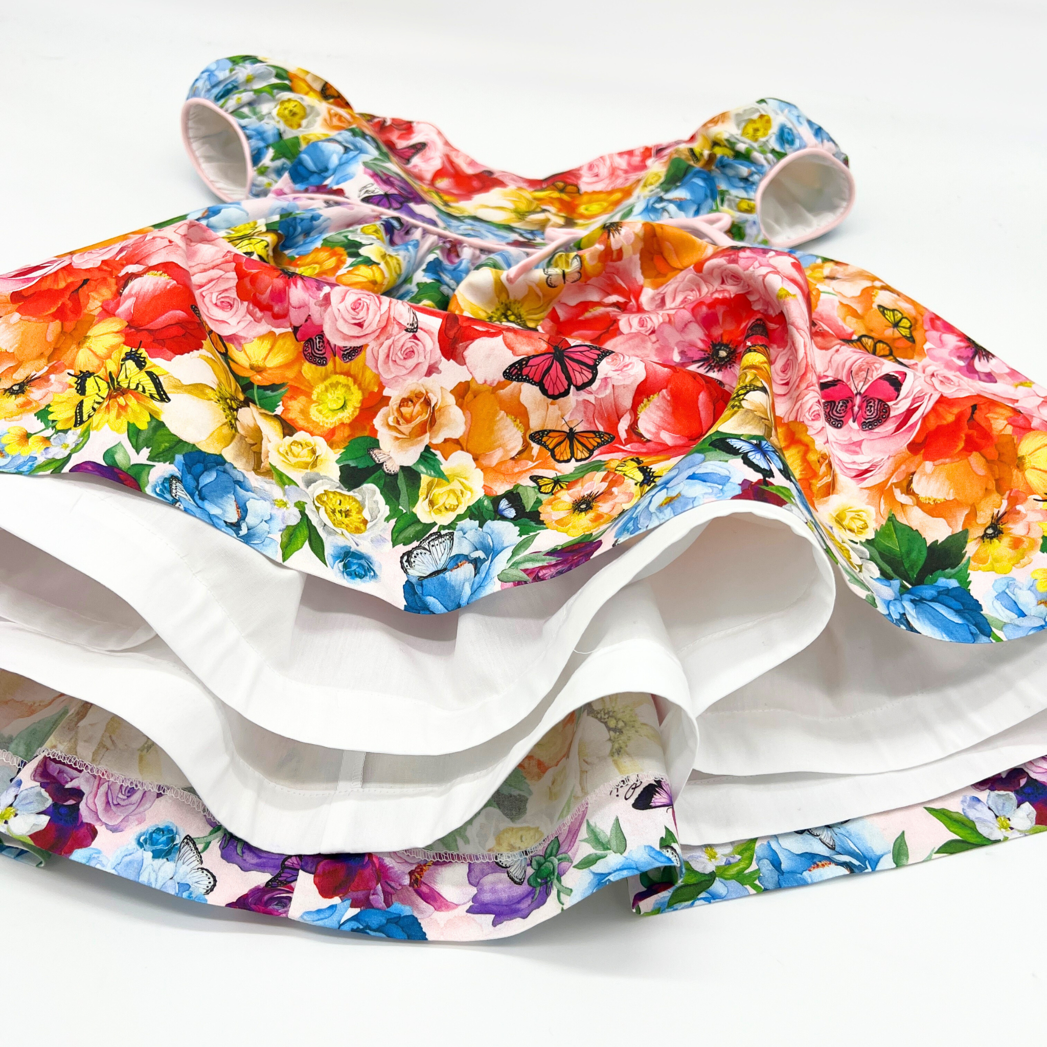 Close-up of the Rainbow Bloom Dress showcasing its full twirl effect, layered skirt lining, and vibrant floral and butterfly print.