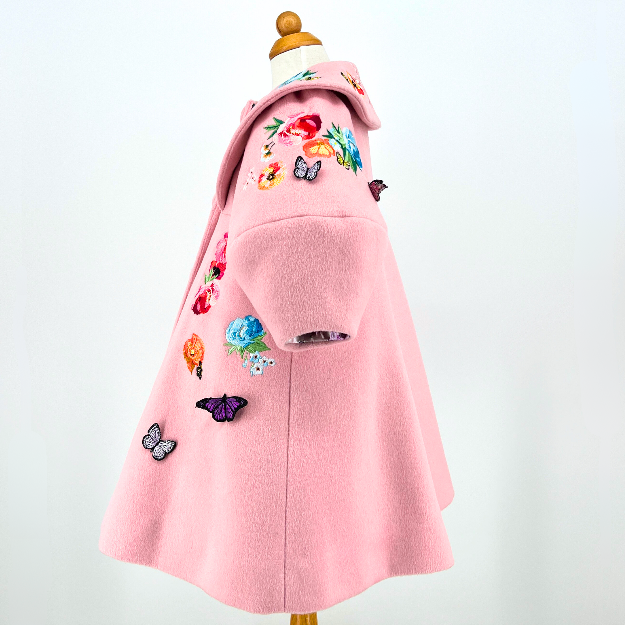 Side view of Rainbow Bloom Girls Coat in pink wool with floral embroidery and 3D butterfly details