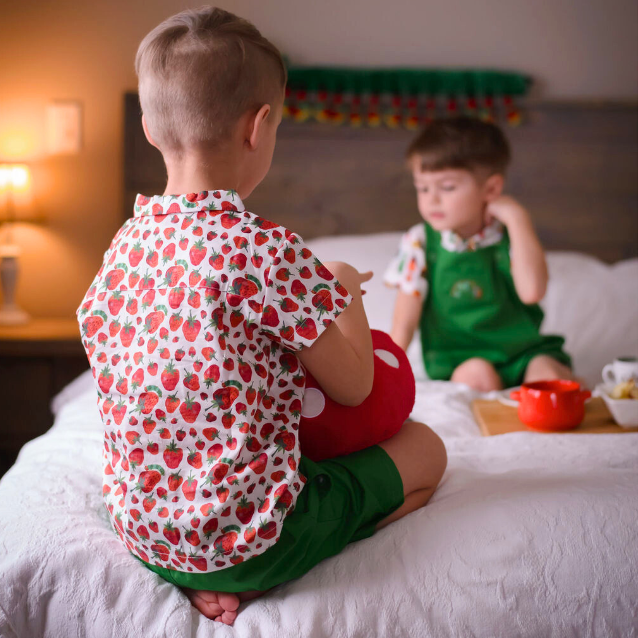 Child seen from the back wearing a strawberry print button-up shirt from The Very Hungry Caterpillar collection, paired with green shorts