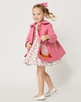 Model wearing pink coat with matching pink dog dress.