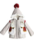 Two white llamas on tan wool coat with red pom pom on top of the hood.