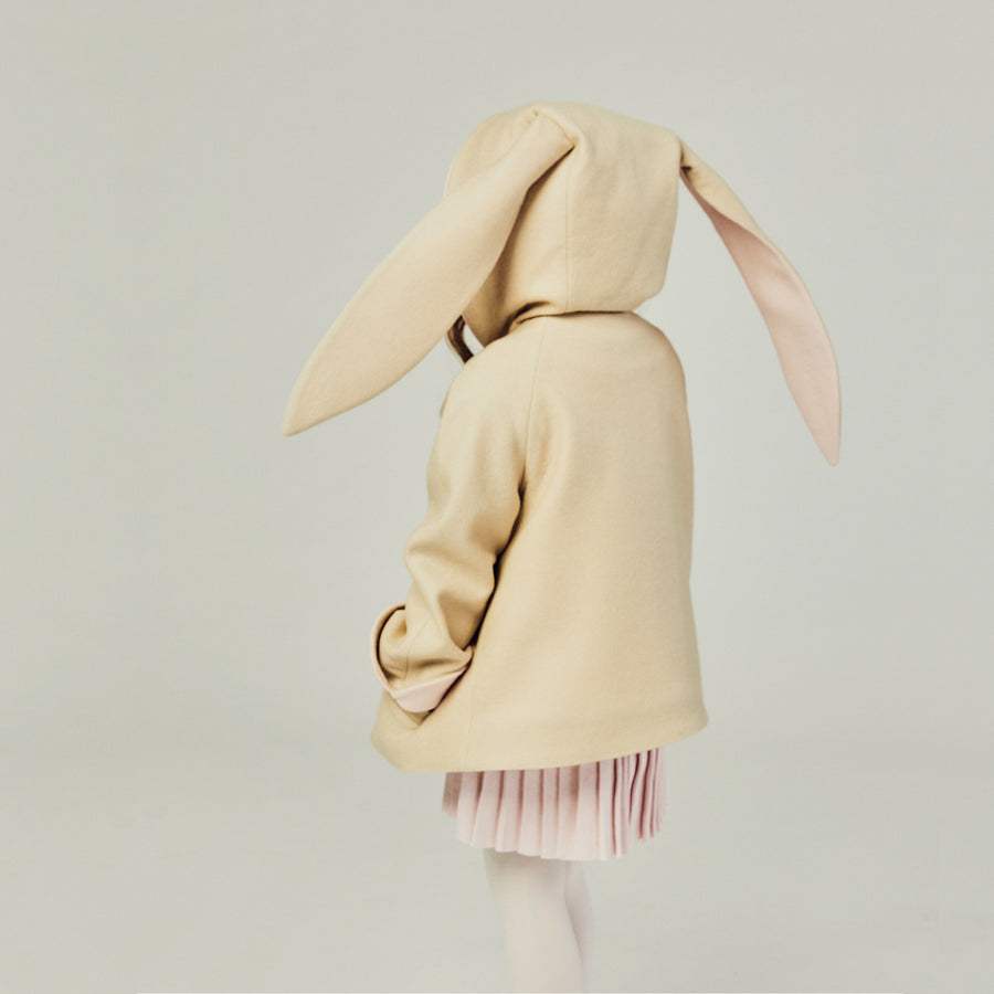 Back view of the tan bunny coat on the model, displaying floppy bunny ears with the hood up.