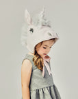 side view of girl modeling a Unicorn hat tied as a bow underneath her chin.