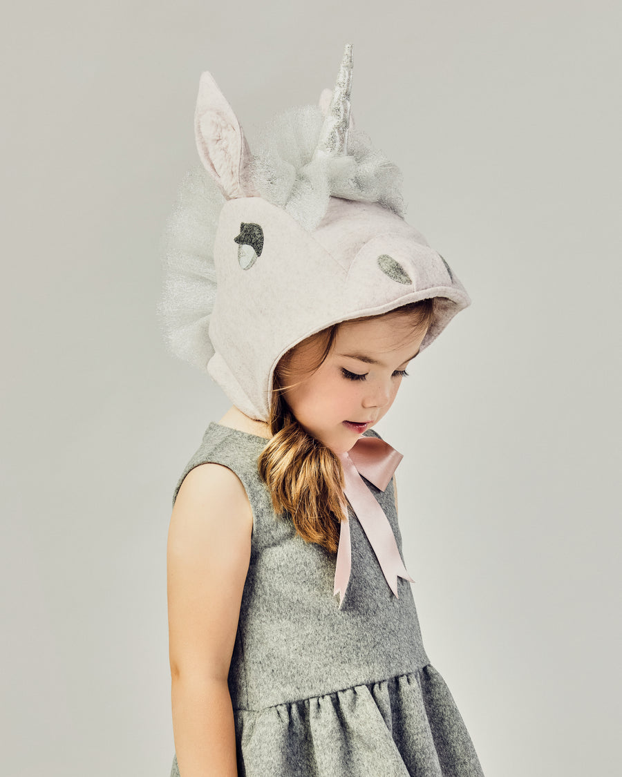 side view of girl modeling a Unicorn hat tied as a bow underneath her chin.