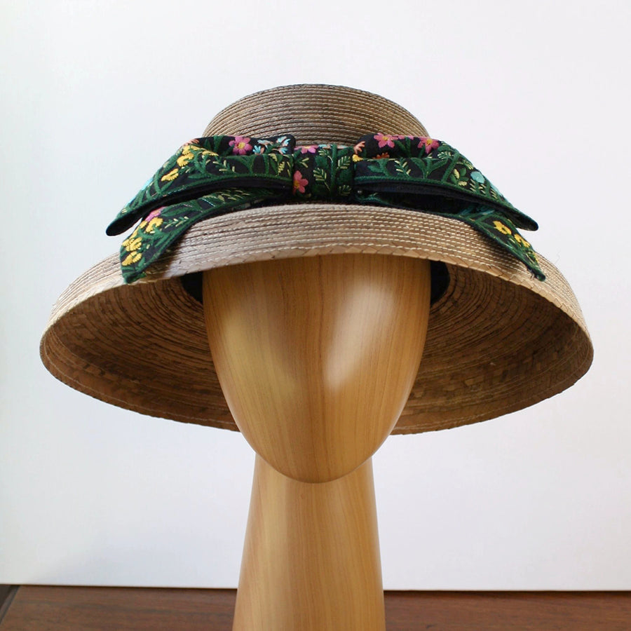 Front view of Audrey Garden Hat with floral embroidered bow, handwoven from natural palm with wide brim for sun protection