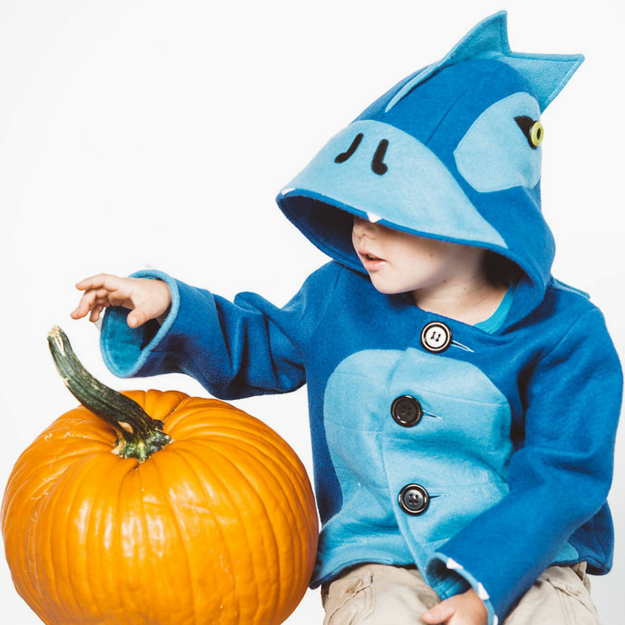 a boy wearing the Blithe Blue Dinosaur Coat , a cozy wool blend jacket with a hood, button closure, and playful dinosaur design