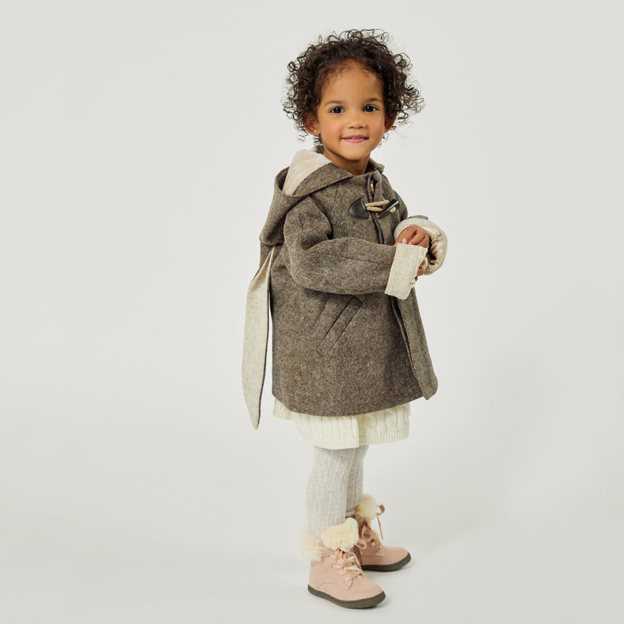 Toddler girl in little Goodall brown wool bunny coat with floppy ears, toggle closures, and a hood, standing in profile