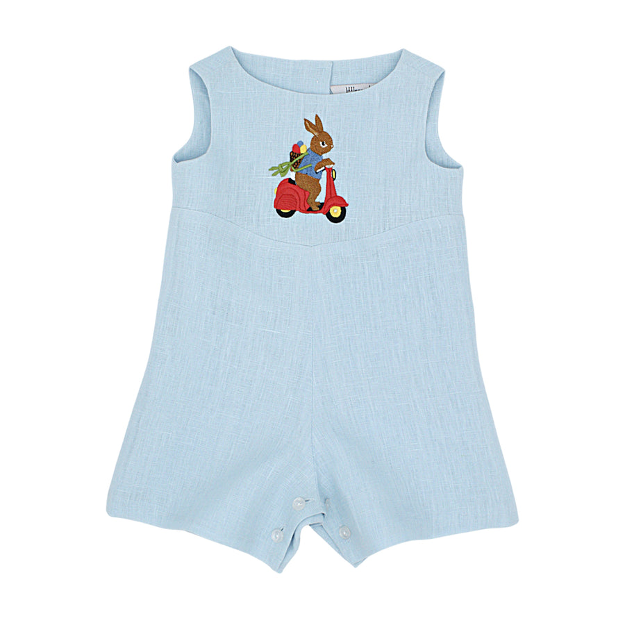 Light blue linen baby romper with embroidered bunny riding a red scooter, featuring back buttons and snap closures. Heirloom-quality toddler outfit.