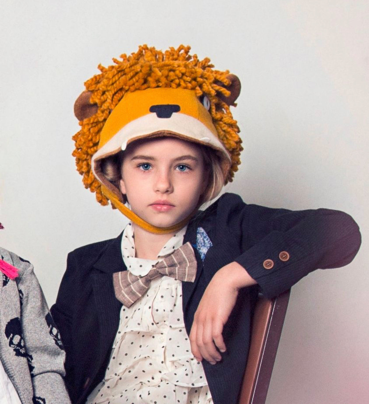 boy wearing a handmade wool-blend felt lion hat with a sherpa lining, earflaps, and a velcro chin strap, featuring a playful yarn mane.